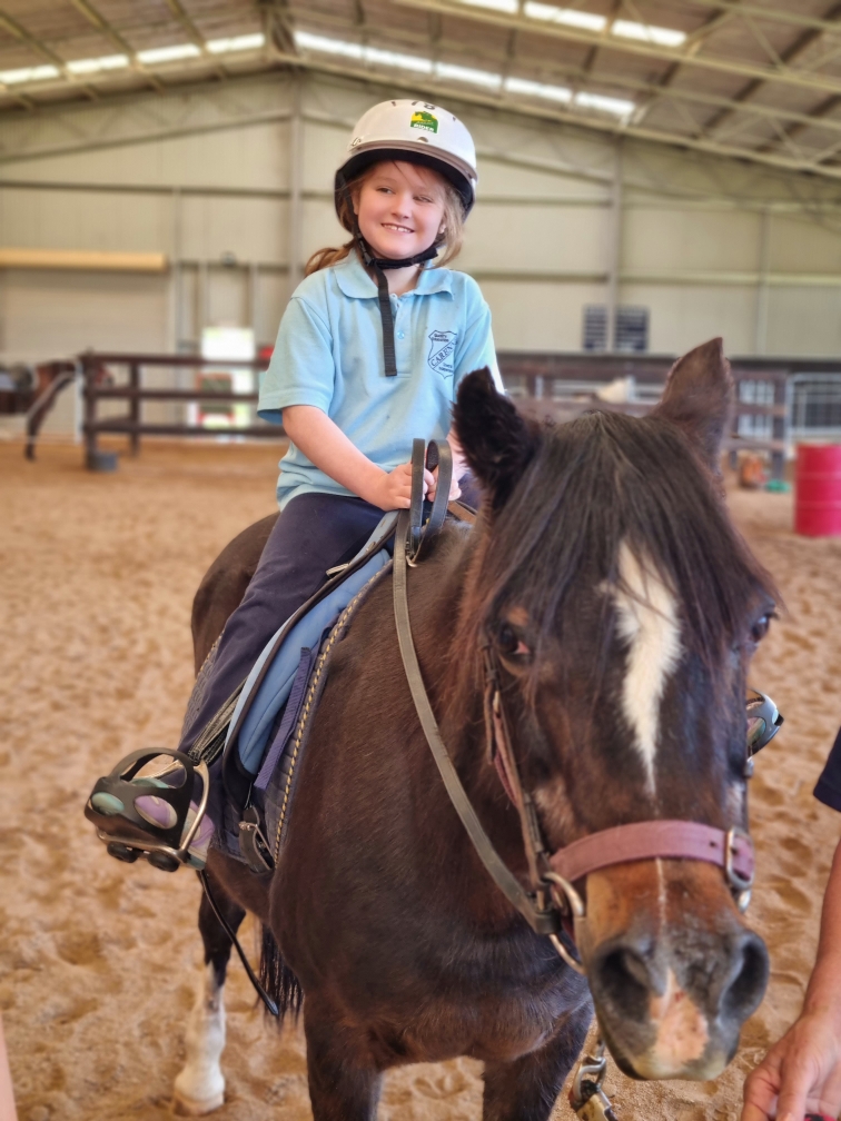 Smiling child with disability riding a horse